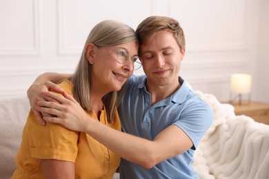 Photo of Son hugging his happy mother at home