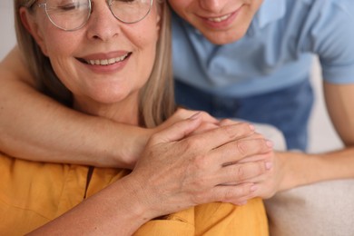 Photo of Son hugging his happy mother indoors, closeup