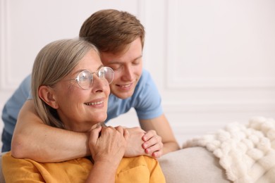 Photo of Son hugging his happy mother at home. Space for text