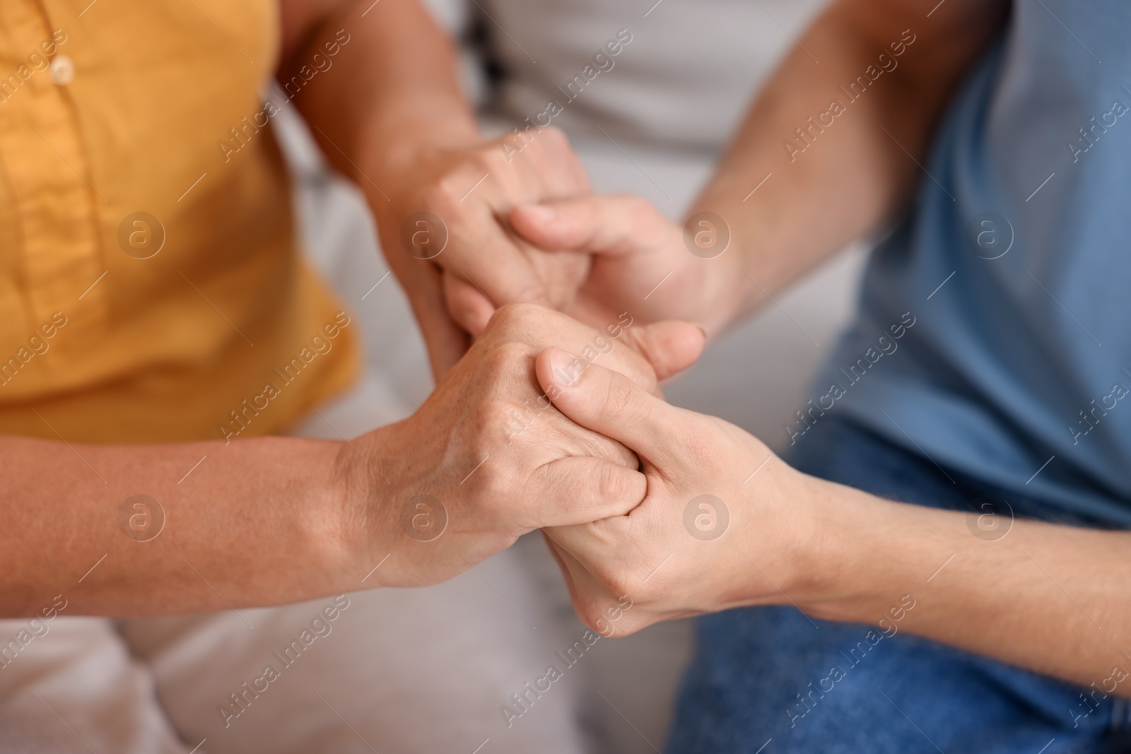 Photo of Son and his mother holding hands indoors, closeup