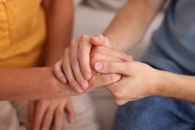 Photo of Son and his mother holding hands indoors, closeup