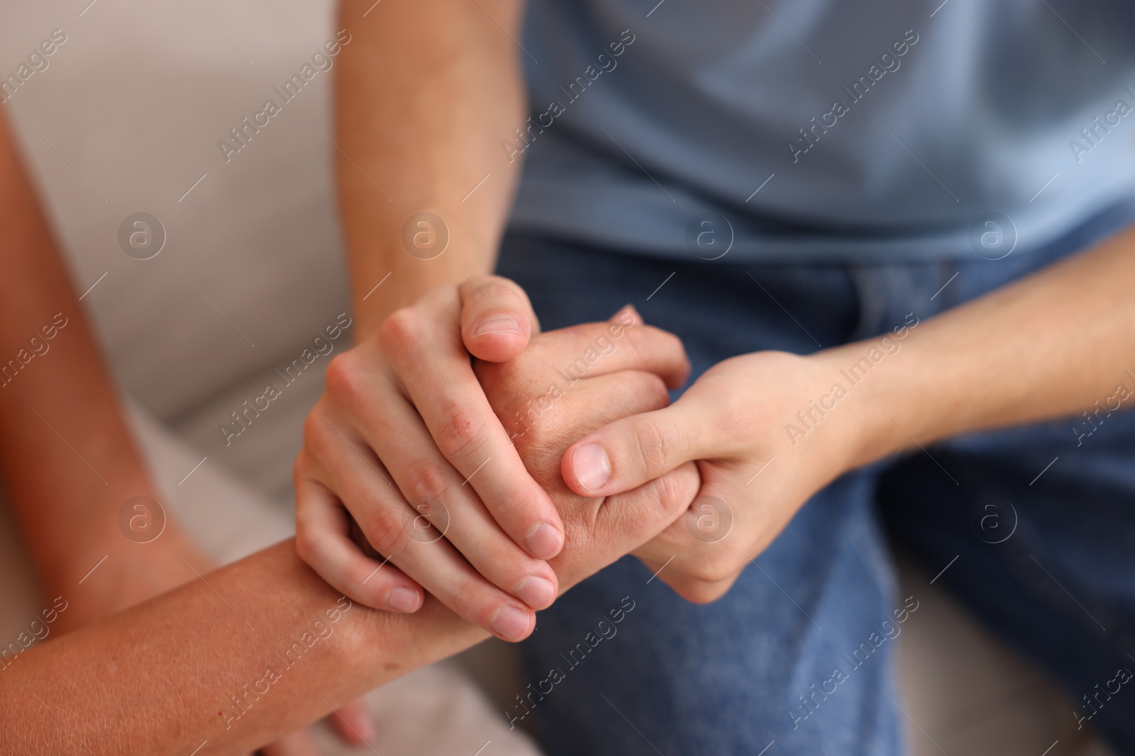 Photo of Son and his mother holding hands indoors, closeup