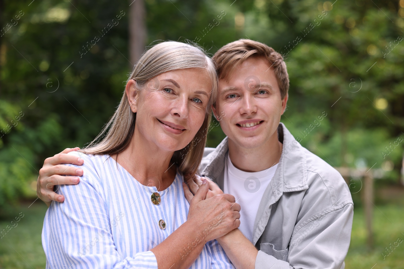 Photo of Family portrait of happy mother and her son holding hands outdoors