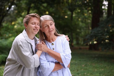 Photo of Mother and her happy son outdoors, space for text. Family bonding