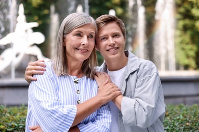 Photo of Smiling mother and her son in front of fountain outdoors. Family bonding