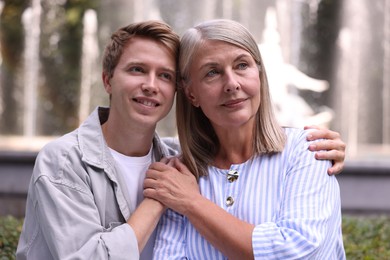 Photo of Mother and her son in front of fountain outdoors. Family bonding