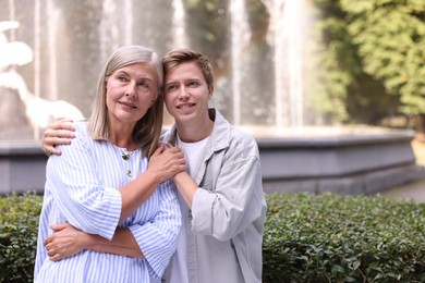 Photo of Mother and her son in front of fountain outdoors, space for text. Family bonding