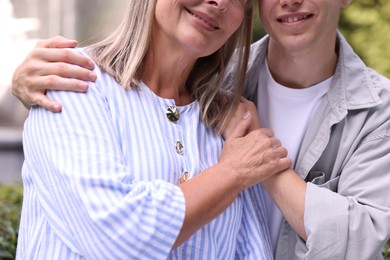 Photo of Smiling mother and her son outdoors, closeup. Family bonding