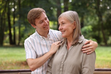 Photo of Smiling mother and her son in park. Family bonding