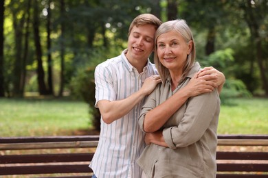Photo of Smiling mother and her son in park, space for text. Family bonding