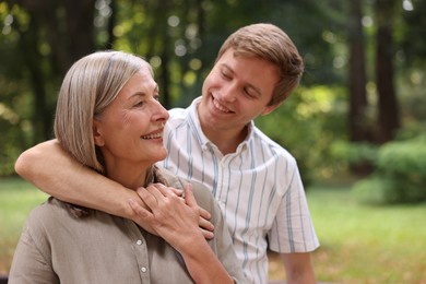 Photo of Smiling mother and her son in park, space for text. Family bonding
