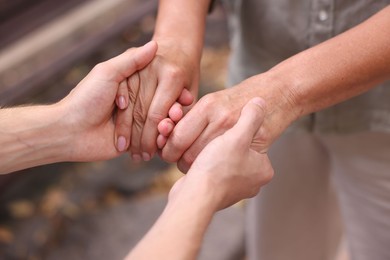 Photo of Son and his mother holding hands outdoors, closeup