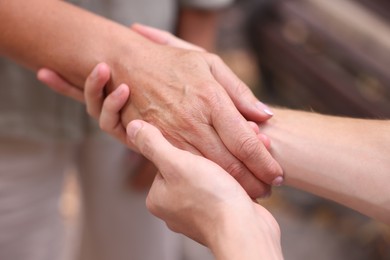Photo of Son and his mother holding hands outdoors, closeup