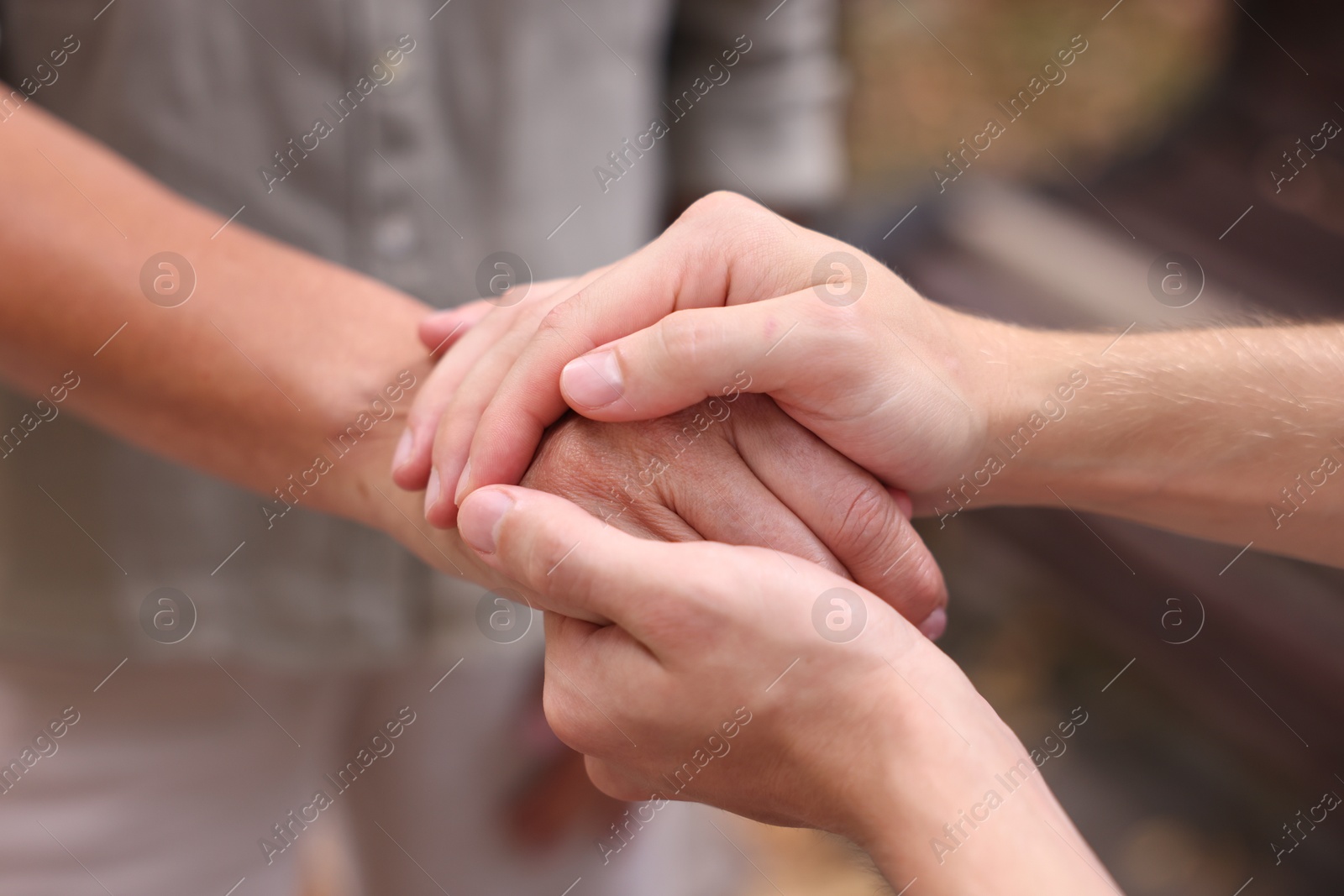 Photo of Son and his mother holding hands outdoors, closeup