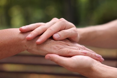 Photo of Son and his mother holding hands outdoors, closeup