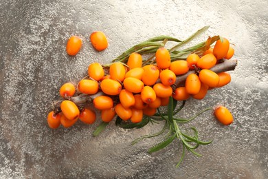 Photo of Fresh sea buckthorn berries and leaves on grey table, top view