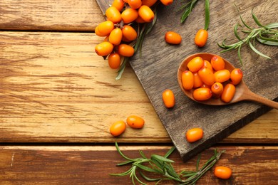 Photo of Fresh sea buckthorn berries, spoon and leaves on wooden table, flat lay. Space for text