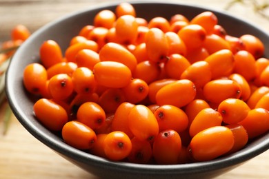 Photo of Fresh sea buckthorn berries in bowl on table, closeup