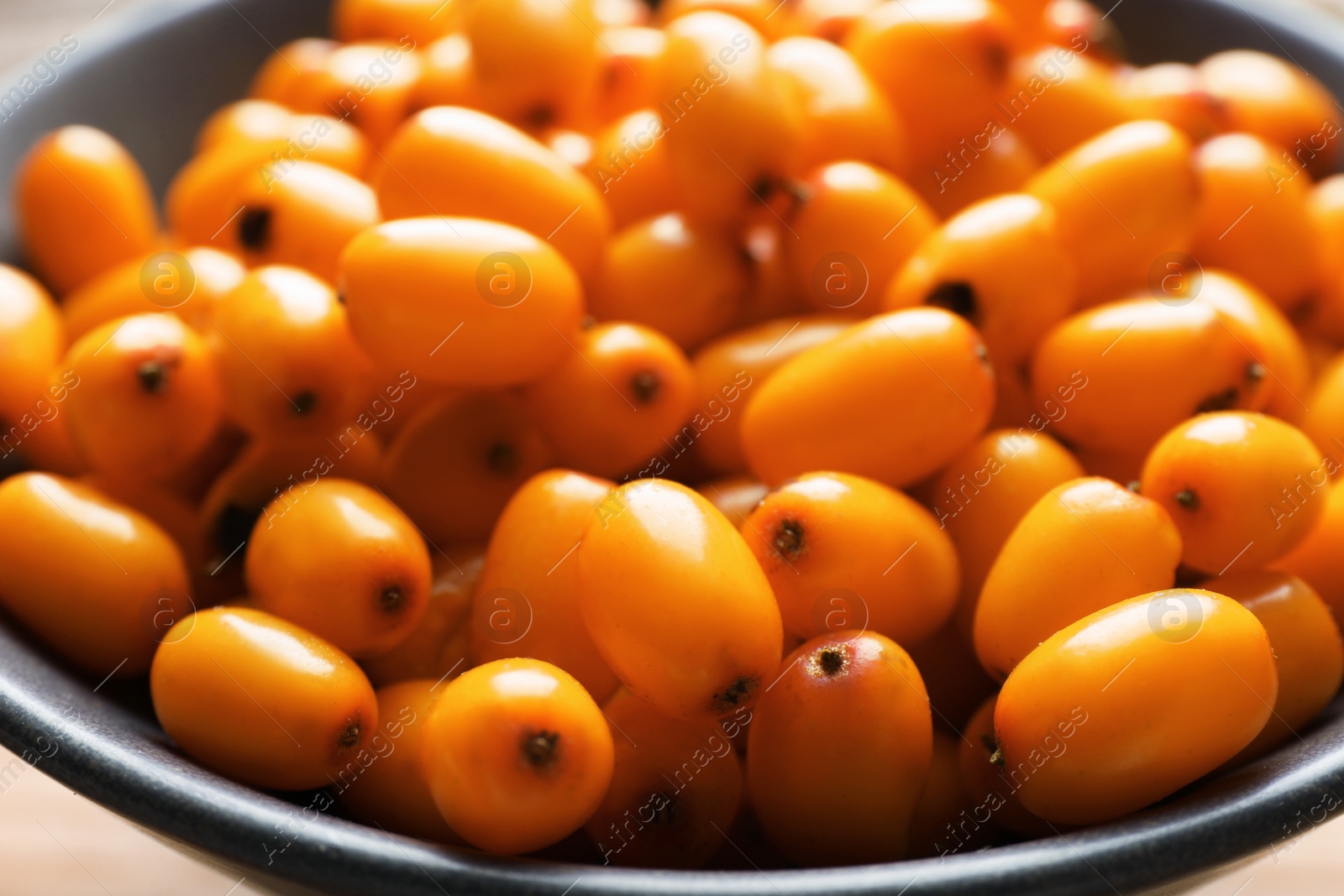 Photo of Fresh sea buckthorn berries in bowl on table, closeup