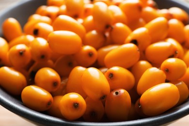 Photo of Fresh sea buckthorn berries in bowl on table, closeup