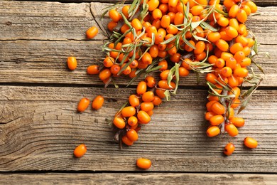 Photo of Fresh sea buckthorn berries with leaves on wooden table, flat lay