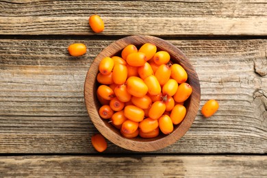 Photo of Fresh sea buckthorn berries in bowl on wooden table, top view