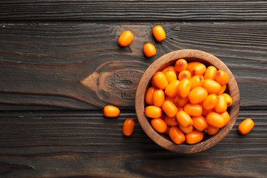 Photo of Fresh sea buckthorn berries in bowl on wooden table, flat lay. Space for text
