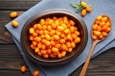 Photo of Fresh sea buckthorn berries in bowl and leaves on wooden table, flat lay