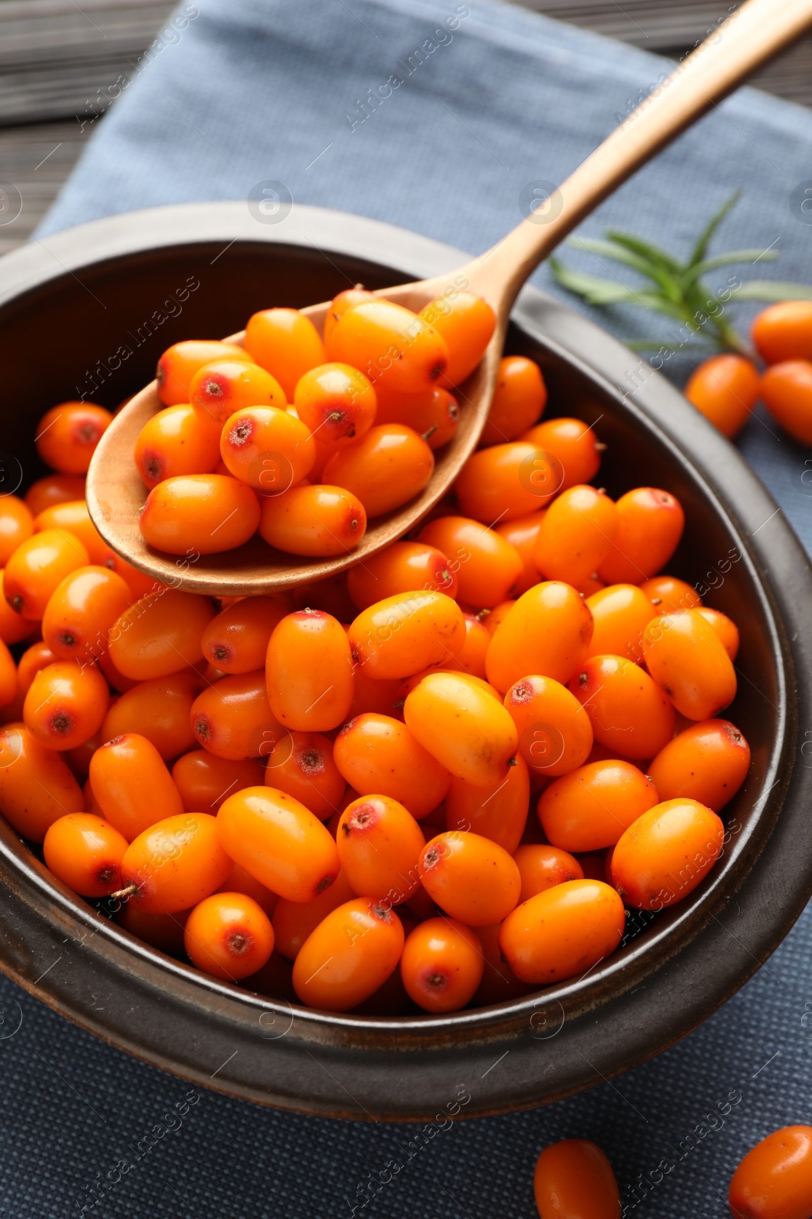 Fresh sea buckthorn berries in bowl and leaves on table, closeup Photo of Fresh sea buckthorn berries in bowl and leaves on table, closeup