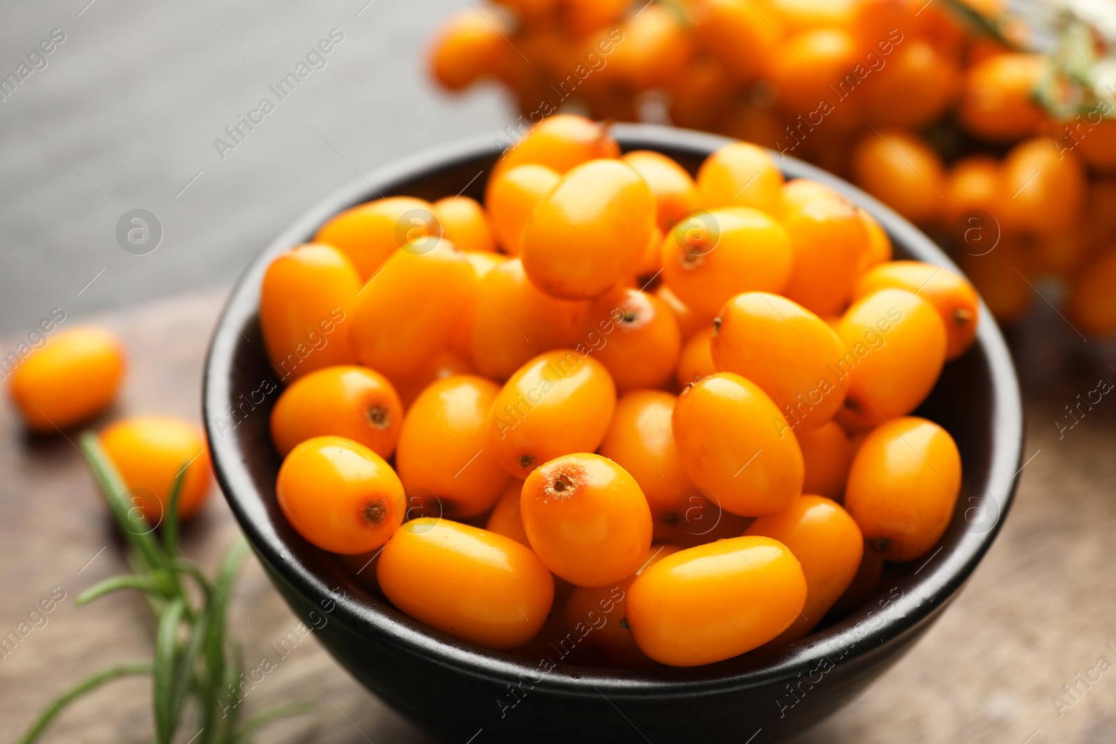 Photo of Fresh sea buckthorn berries with leaves on table, closeup