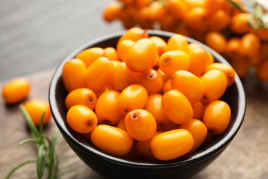 Photo of Fresh sea buckthorn berries with leaves on table, closeup