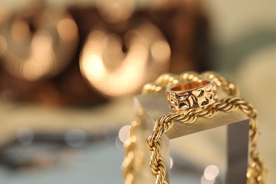 Photo of Beautiful gold jewelry on blurred background, closeup. Space for text