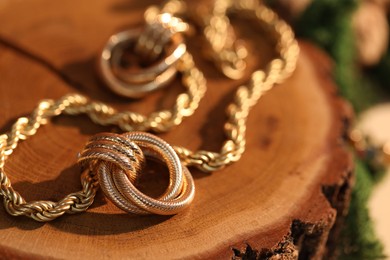 Photo of Beautiful gold earrings and chain on wood, closeup