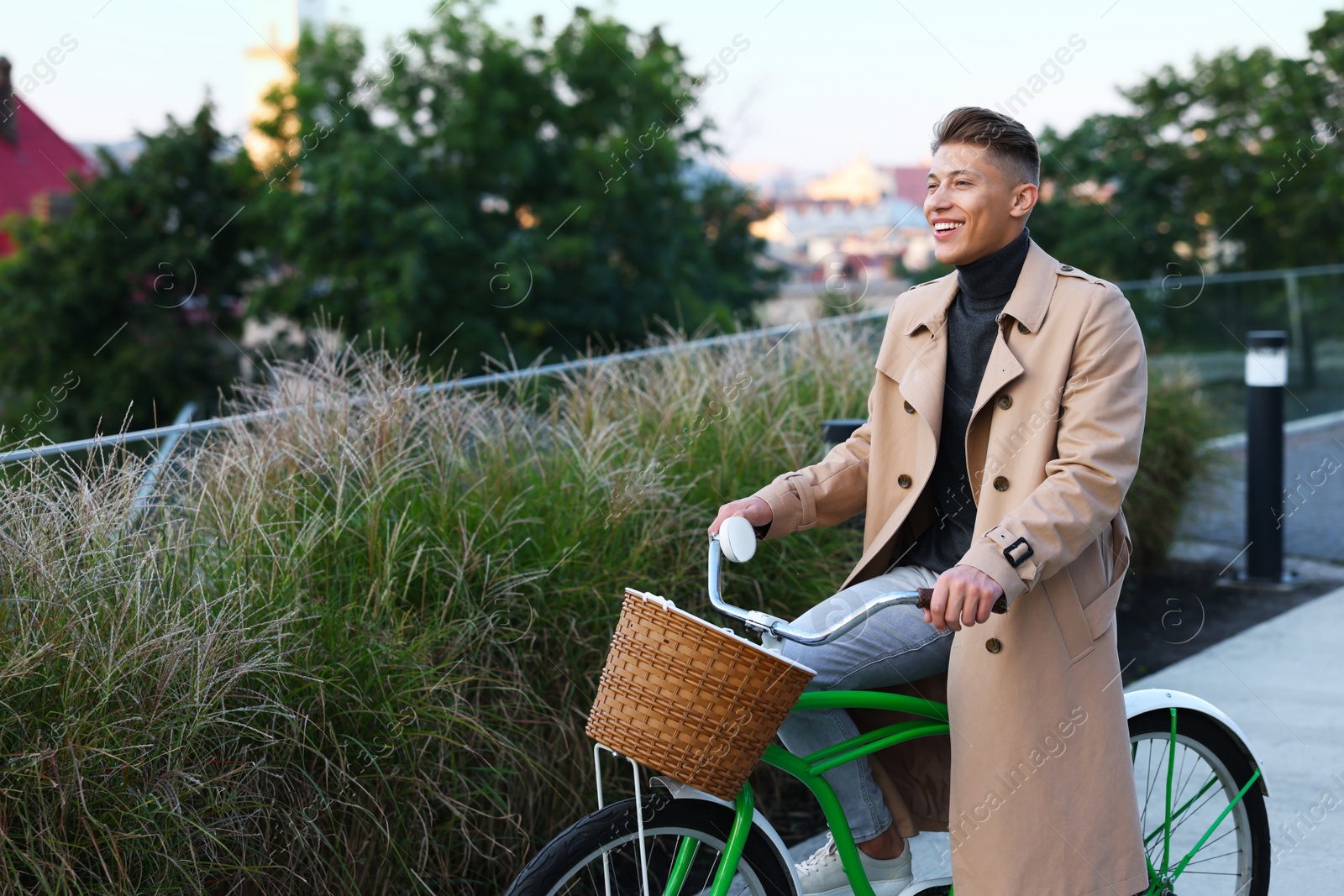 Photo of Happy man riding bicycle on city street. Space for text