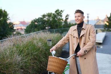 Photo of Happy man walking his bicycle on city street. Space for text