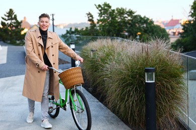 Photo of Happy man walking his bicycle on city street. Space for text