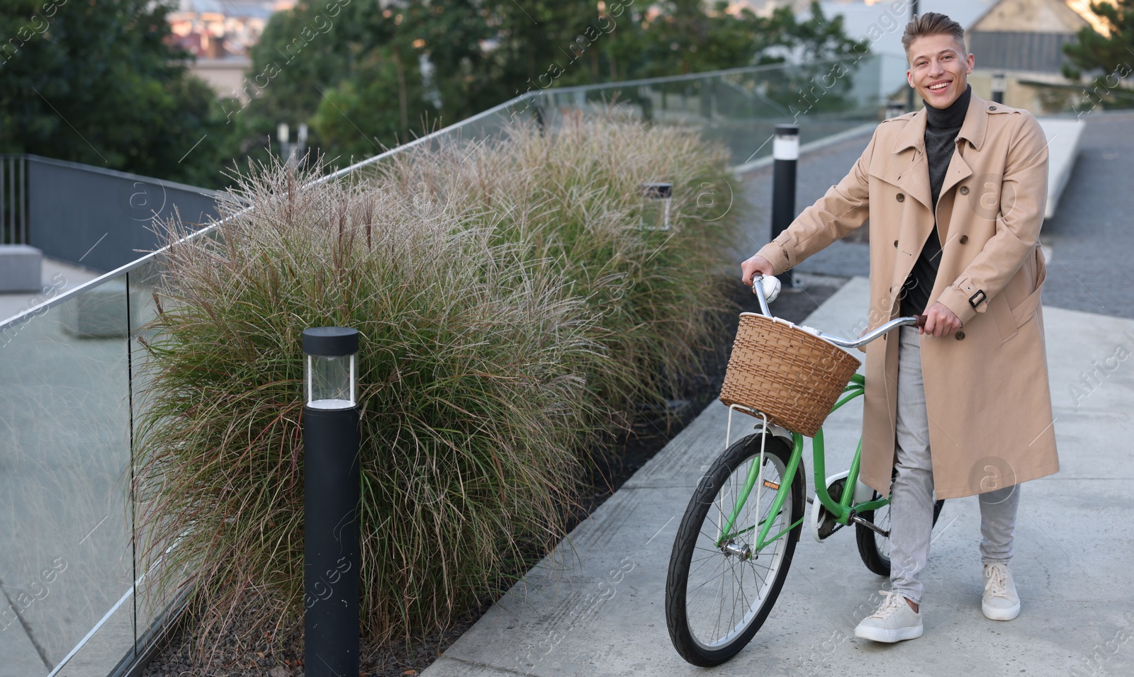 Photo of Happy man walking his bicycle on city street. Space for text