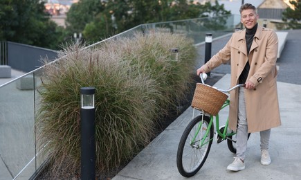 Photo of Happy man walking his bicycle on city street. Space for text