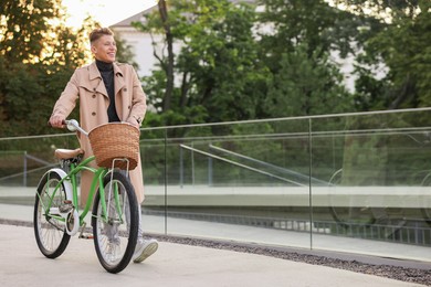 Photo of Happy man walking his bicycle on city street. Space for text