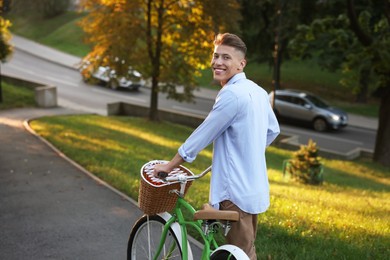 Photo of Happy man walking his bicycle in park on sunny day