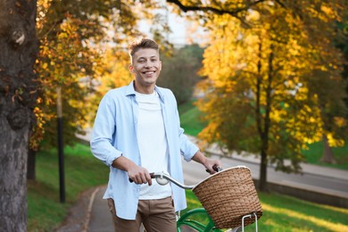 Photo of Happy man walking his bicycle in park on sunny day