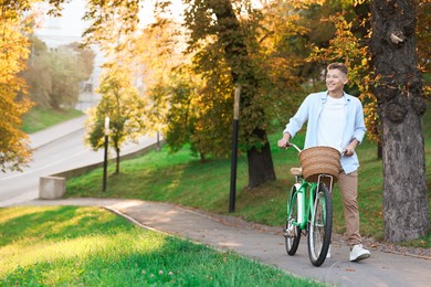 Photo of Happy man walking his bicycle in park on sunny day. Space for text