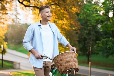 Photo of Happy man walking his bicycle in park on sunny day