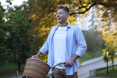 Photo of Happy man walking his bicycle in park on sunny day