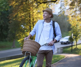 Photo of Happy man walking his bicycle in park on sunny day