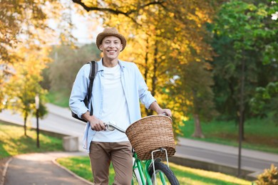 Photo of Happy man walking his bicycle in park on sunny day