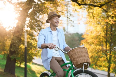 Photo of Happy man riding bicycle in park on sunny day