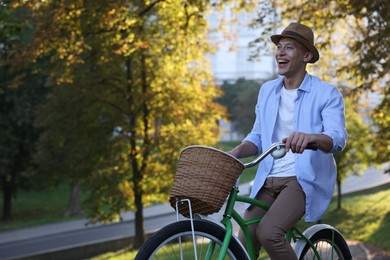 Photo of Happy man riding bicycle in park on sunny day. Space for text