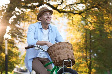 Photo of Happy man riding bicycle in park on sunny day. Space for text