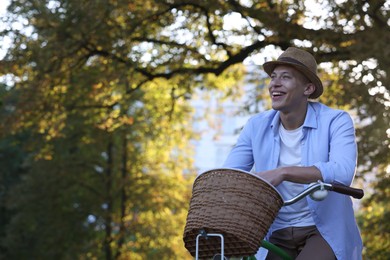 Photo of Happy man riding bicycle in park on sunny day. Space for text